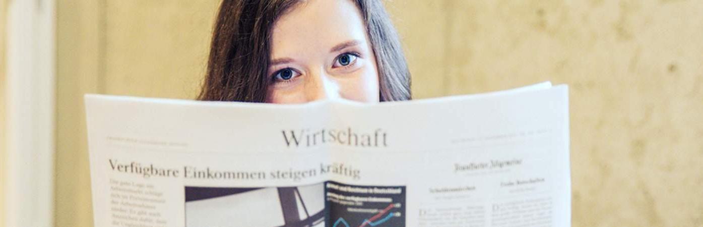 Person holding an open magazine with a chart and German text.