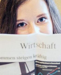 Person holding an open magazine with a chart and German text.