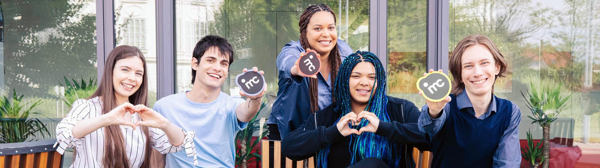  Gruppe von fünf Personen sitzt nebeneinander und macht Handgesten für Liebe und Frieden