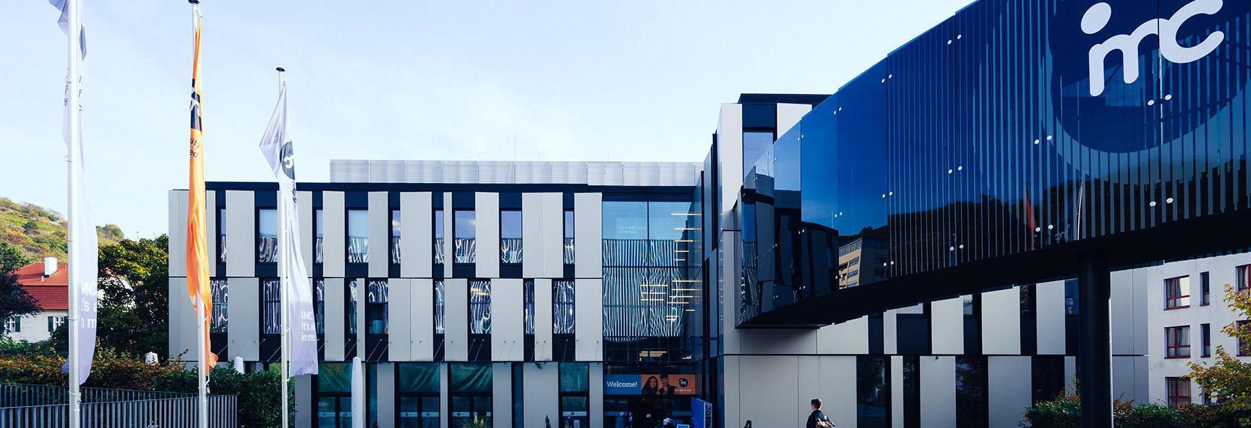 Frontalansicht vom Gebäude G1 am IMC Campus Krems. Die Brücke zwischen Gebäude Trakt G & G1 mit dem großen IMC Logo ist rechts im Bild zu sehen.