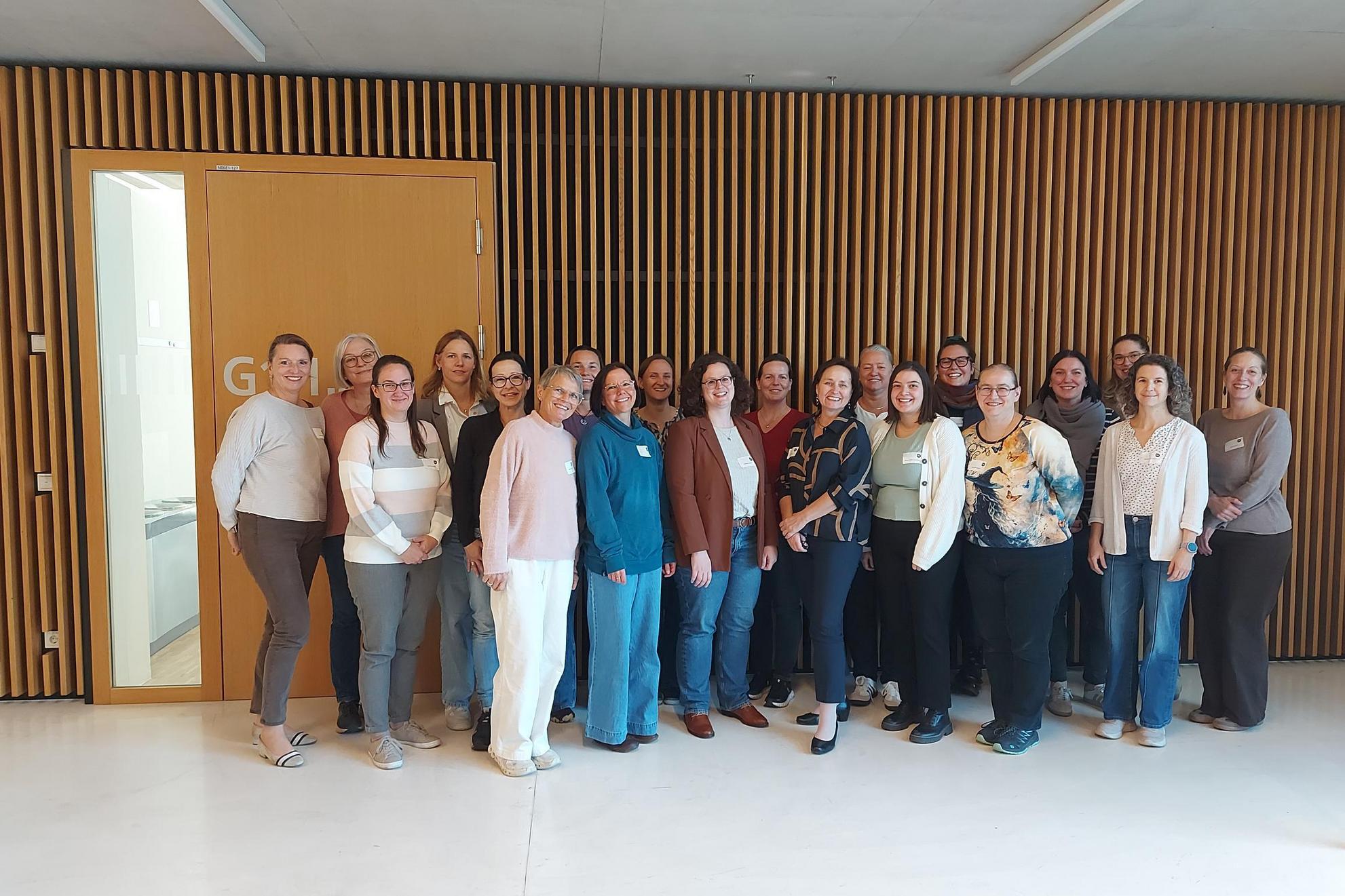 Gruppe von Frauen steht vor Holzwand in einem modernen Gebäude