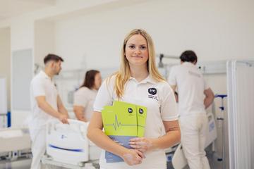 Porträt von Hannah Schodl, die vor einem Krankenbett steht