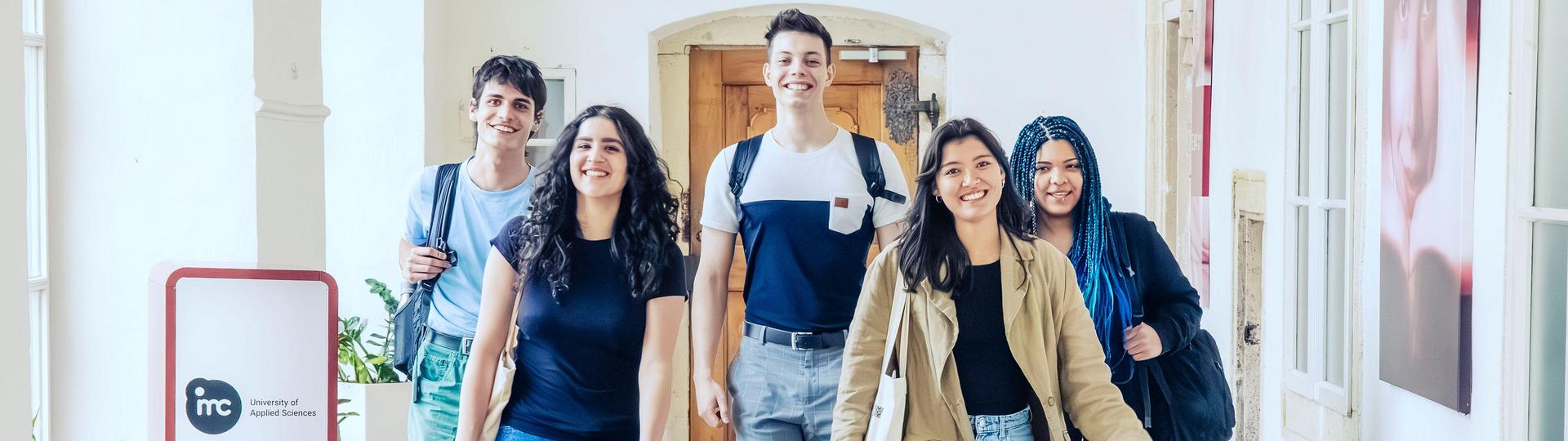 Group of students walking along a corridor and looking into the camera