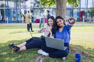 Zwei Studierende sitzen in der Wiese am IMC Campus Krems