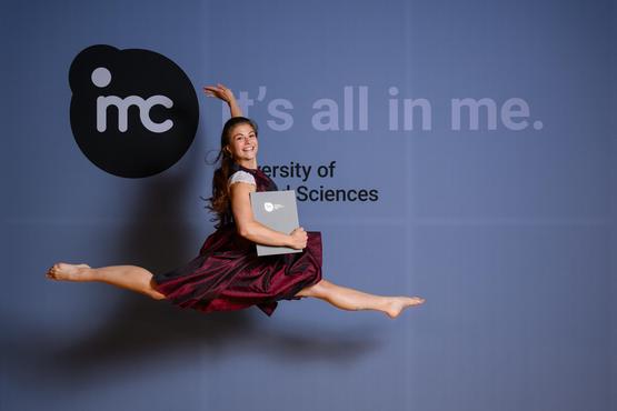 A graduate leaps into the air at her graduation ceremony