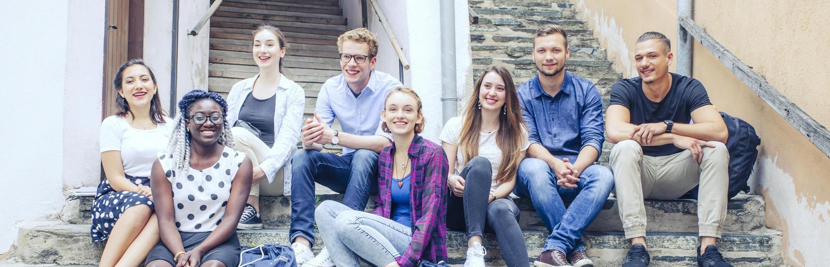Group of seven people sitting on stone steps in an alleyway.