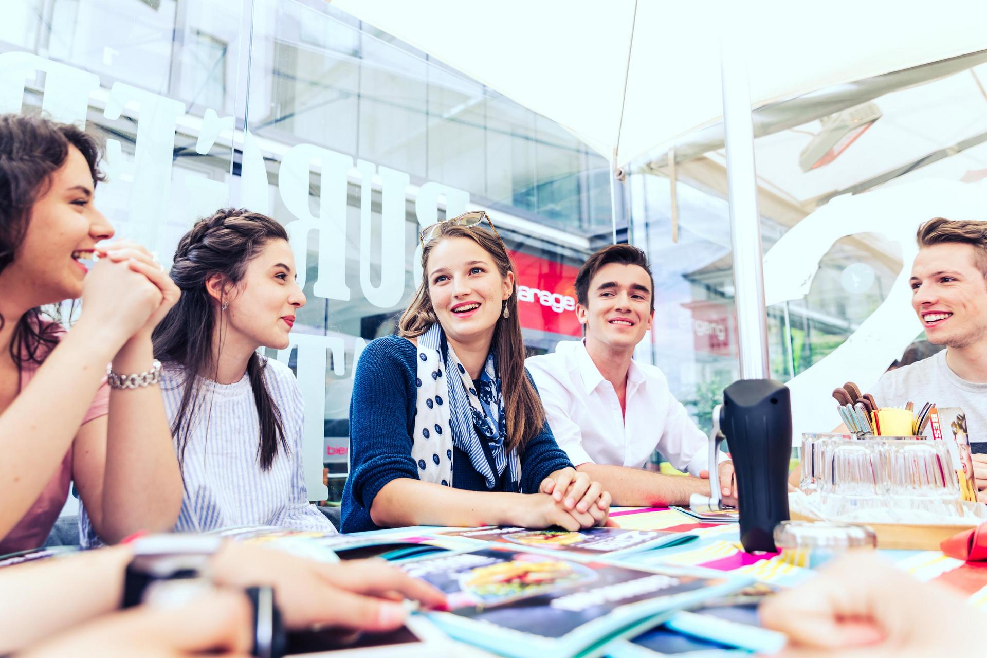 Eine Gruppe von Studierenden sitzt im Restaurant und unterhält sich