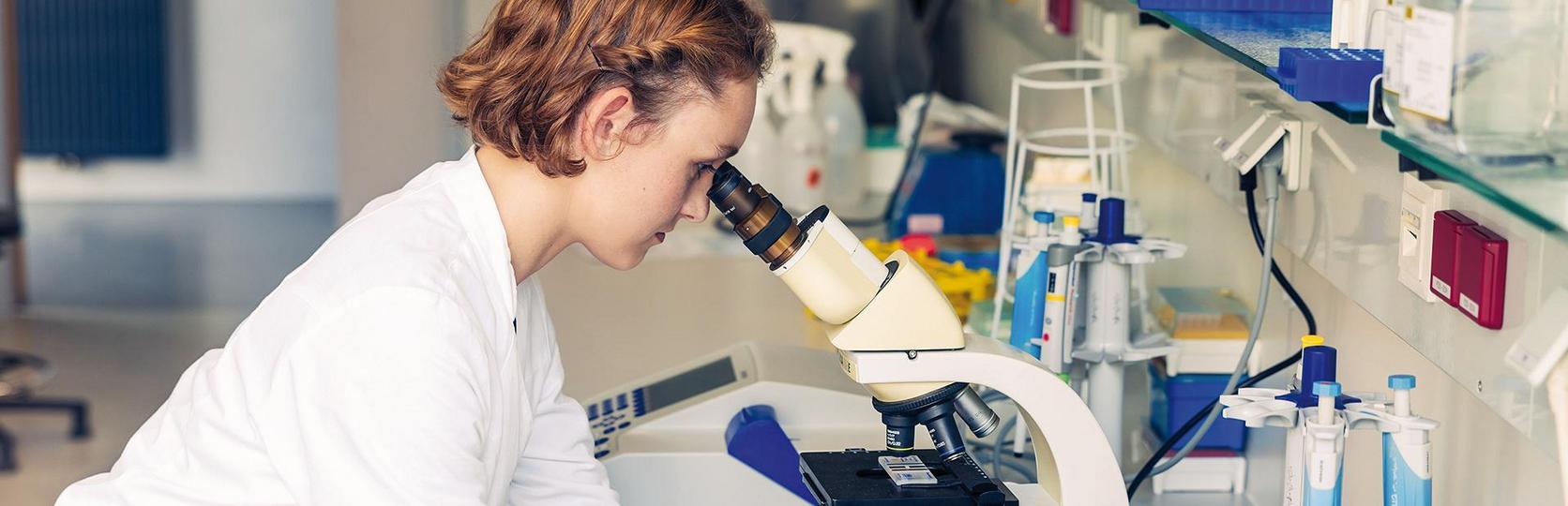 Wissenschaftlerin, die ein Mikroskop in einem Labor benutzt.