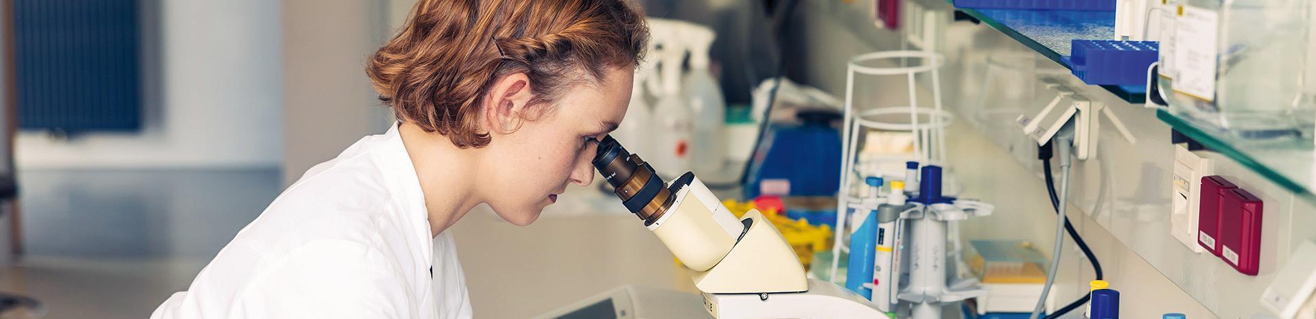 Wissenschaftlerin, die ein Mikroskop in einem Labor benutzt.