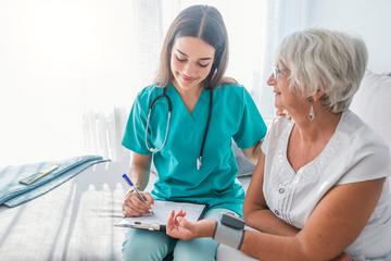 Pflegerin geht Liste mit Patientin durch