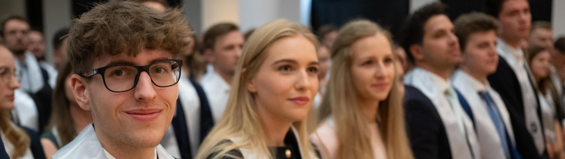 Gruppe von Personen in formeller Kleidung bei einer Sponsion.